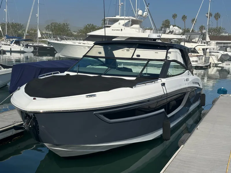 Slide: The Image of A 2021 Cruisers Yachts 38 GLS docked in a marina. It features a sleek design with a black cover. - 18