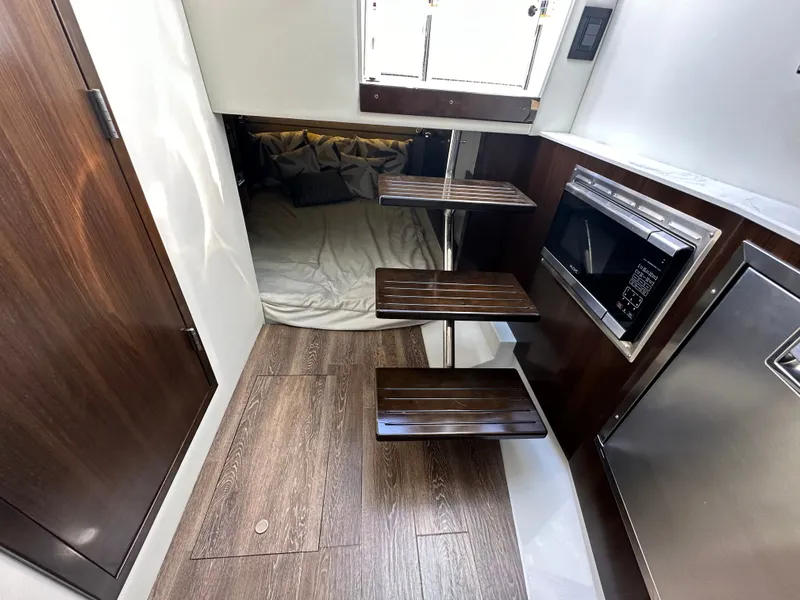Slide: The Image of Interior of a 2021 Cruisers Yachts 38 GLS with wooden steps, microwave, and sleeping area. - 42