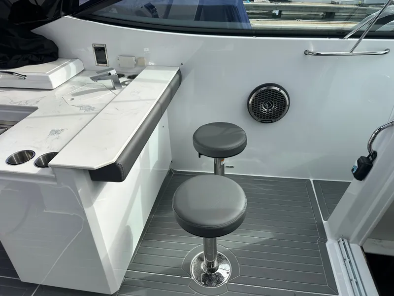 Slide: The Image of The 2021 Cruisers Yachts 38 GLS features a modern interior with gray stools and a sleek table. - 16