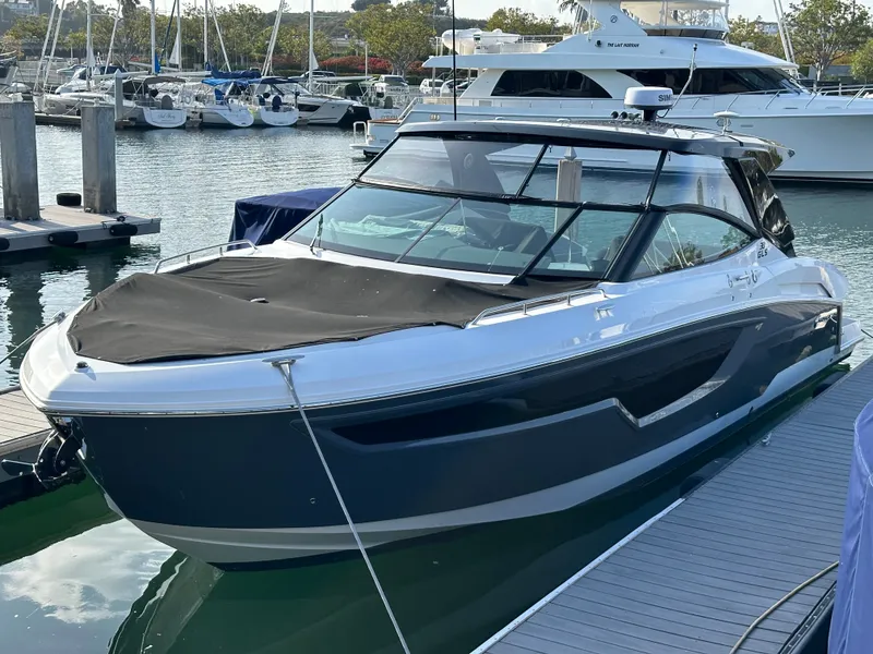 Slide: The Image of A 2021 Cruisers Yachts 38 GLS docked. It features a sleek design with a black cover. - 1