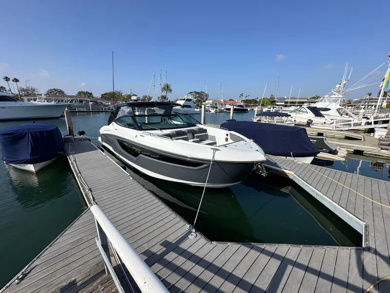 Slide: The Image of A 2021 Cruisers Yachts 38 GLS docked in a sunny marina, surrounded by other boats. - 26