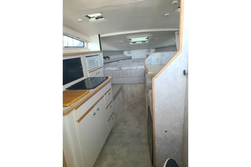 Slide: The Image of Interior of 1998 Bayliner 2855 Ciera Sunbridge, featuring kitchenette and cozy sleeping area. - 12