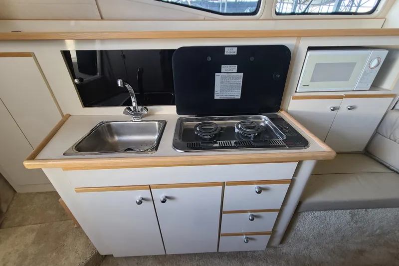 Slide: The Image of Compact kitchen in 1998 Bayliner 2855 Ciera Sunbridge with sink, stove, and microwave. - 8