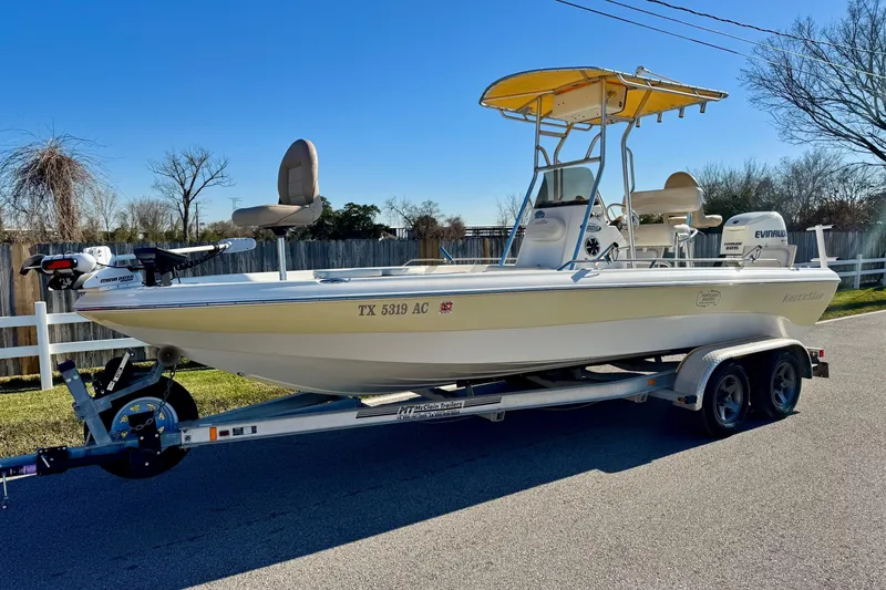 The Image of 2006 NauticStar 2200 NauticBay boat on trailer, featuring Evinrude engine and yellow canopy. - 0
