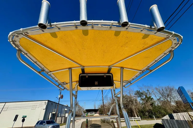 Slide: The Image of 2006 NauticStar 2200 NauticBay boat with yellow canopy and rod holders under clear blue sky. - 10