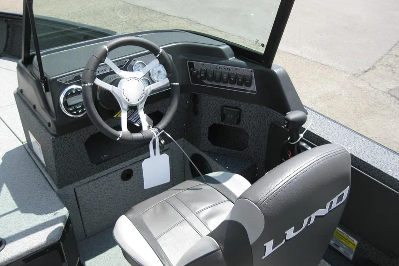 Slide: The Image of 2025 Lund 1875 Impact XS Sport boat interior with steering wheel and dashboard controls. - 11