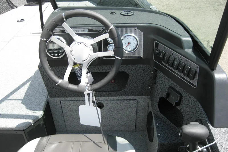 Slide: The Image of 2025 Lund 1875 Impact XS Sport boat dashboard with steering wheel and control panel. - 12