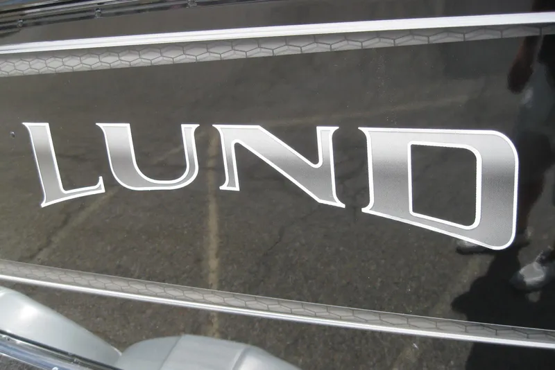 Slide: The Image of 2025 Lund 1875 Impact XS Sport boat logo on sleek black surface. - 3