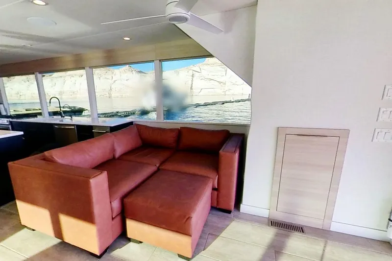 Slide: The Image of Modern houseboat interior with brown sectional sofa, large windows, and scenic water view. Adonia Radiance Share #3, 2022. - 3