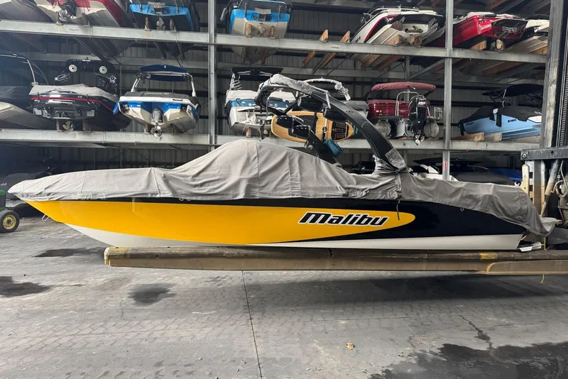 Slide: The Image of 2005 Malibu Wakesetter VLX boat in storage, covered, with yellow and black design. - 36