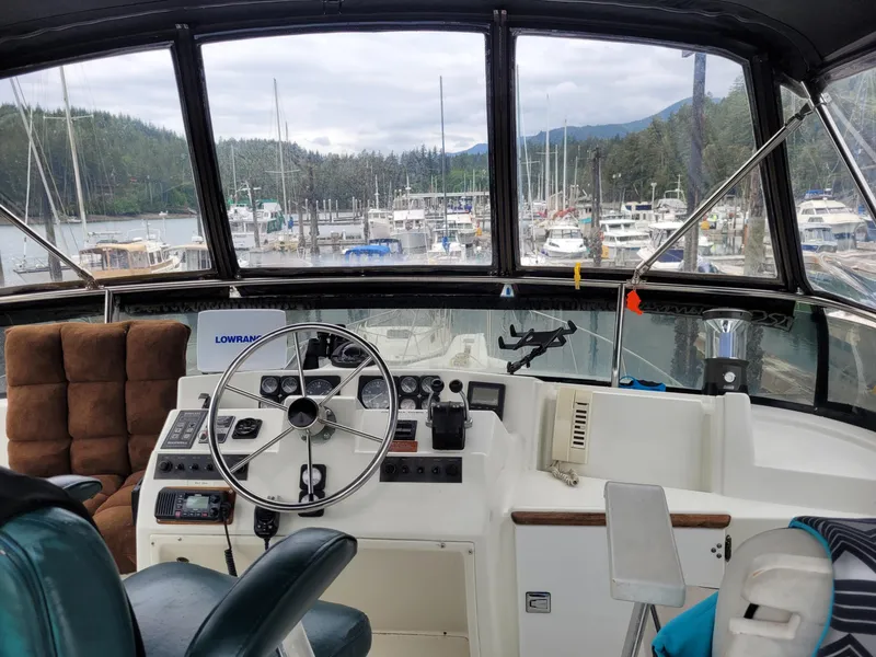 Slide: The Image of 1991 Tollycraft Euro Sport Sedan helm with marina view, featuring steering wheel and control panel. - 20