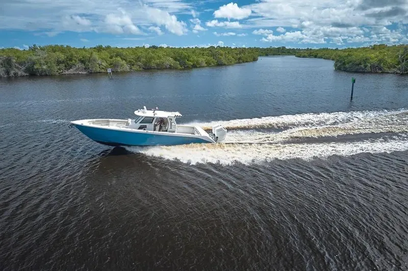 Slide: The Image of 2022 Solace 41 CS boat cruising on a scenic river under a blue sky. - 2