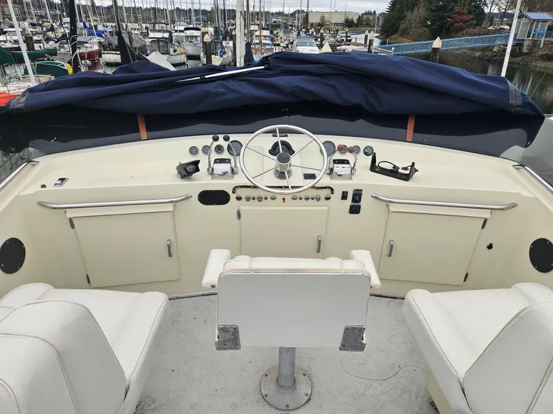 Slide: The Image of 1978 Tollycraft 37 Sport Sedan boat helm with white seating and marina background. - 24