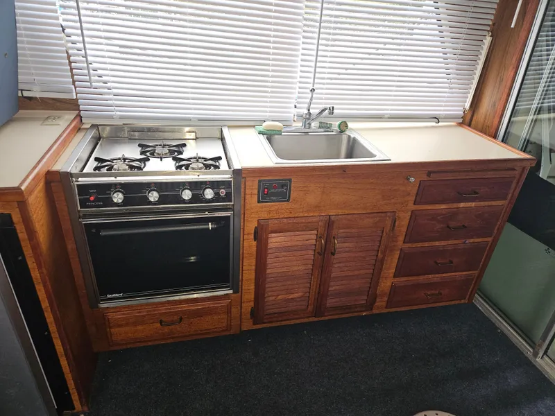 Slide: The Image of 1978 Tollycraft 37 Sport Sedan kitchen with stove, sink, and wooden cabinetry. - 11