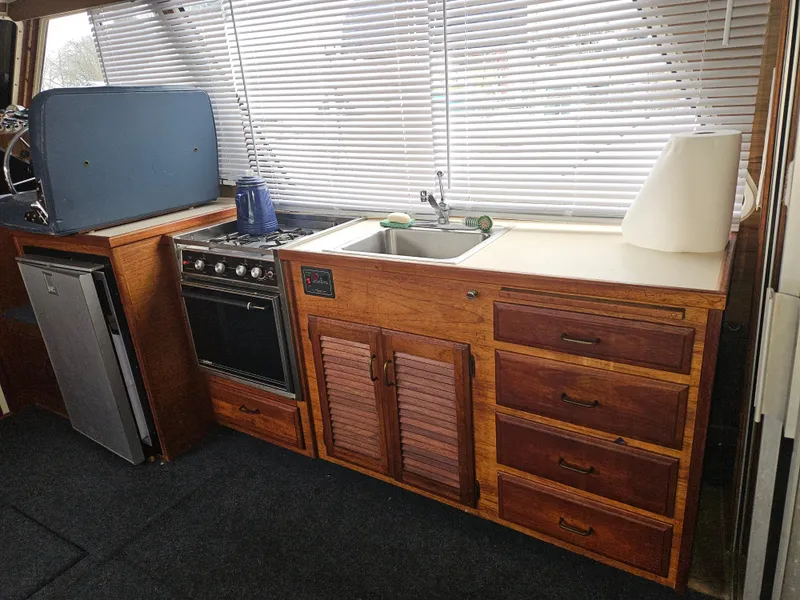 Slide: The Image of 1978 Tollycraft 37 Sport Sedan kitchen with stove, sink, and wooden cabinetry. - 8