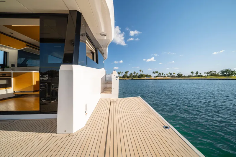 Slide: The Image of 2023 Pardo Yachts E60 deck with dining area overlooking serene water and palm trees. - 21