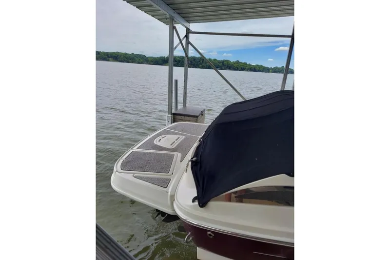 Slide: The Image of 2012 Sea Ray 240 Sundeck docked under a canopy on a calm lake. - 38