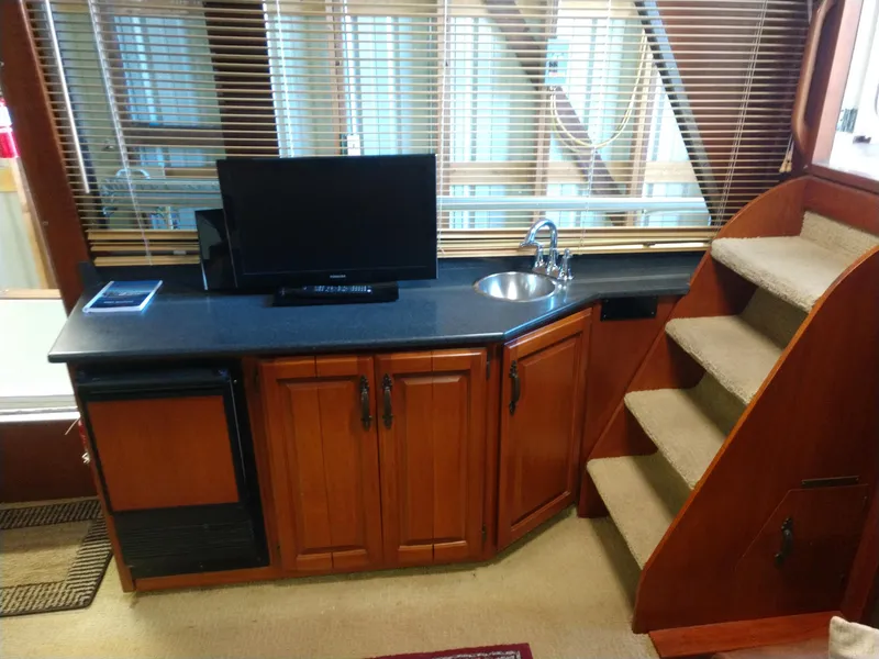 Slide: The Image of 1981 Tollycraft 43 Motoryacht interior with TV, sink, cabinets, and carpeted stairs. - 15