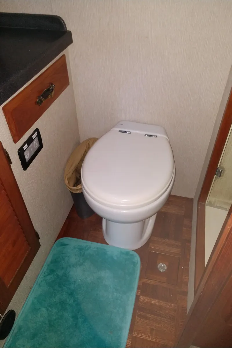 Slide: The Image of 1981 Tollycraft 43 Motoryacht bathroom with toilet, teal mat, and wooden cabinetry. - 30