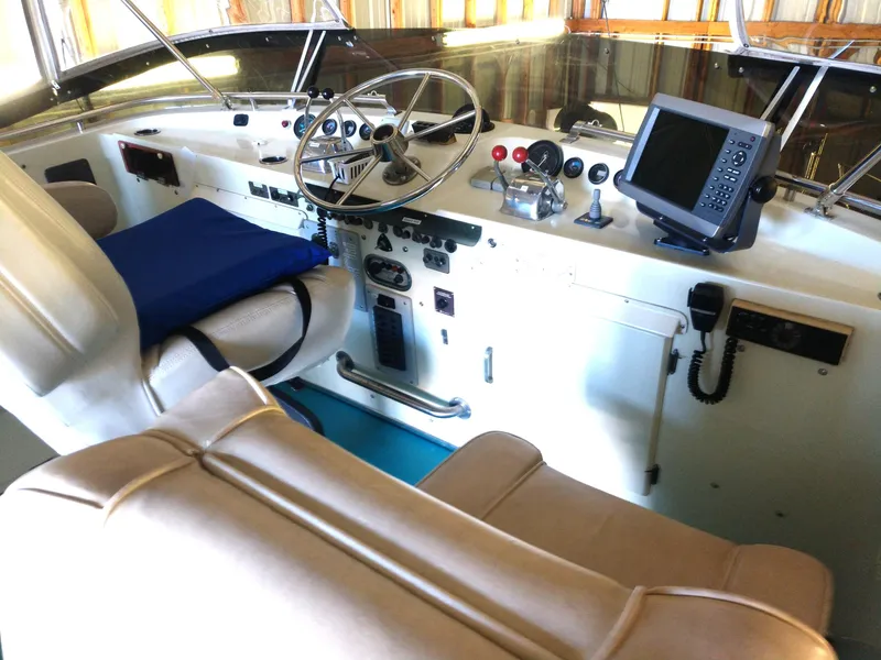 Slide: The Image of 1981 Tollycraft 43 Motoryacht helm with steering wheel, navigation equipment, and cushioned seating. - 4