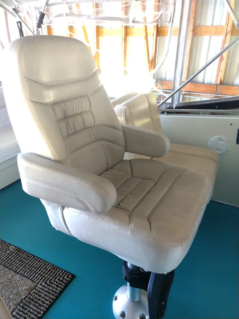 Slide: The Image of Captain's chair on 1981 Tollycraft 43 Motoryacht, featuring beige upholstery and adjustable armrests. - 5