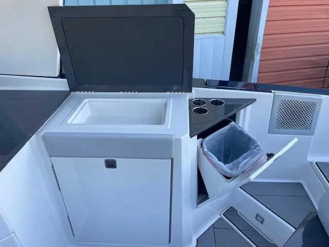 Slide: The Image of Aviara AV 32-OB 2022 boat interior with sink, cup holders, and trash compartment. - 21