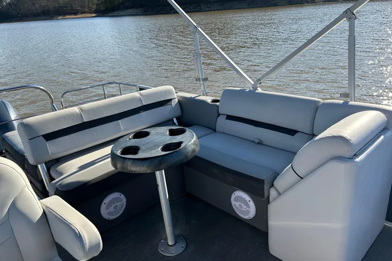 Slide: The Image of 2022 Godfrey Sweetwater 2286 C pontoon boat interior with seating and table on a lake. - 14