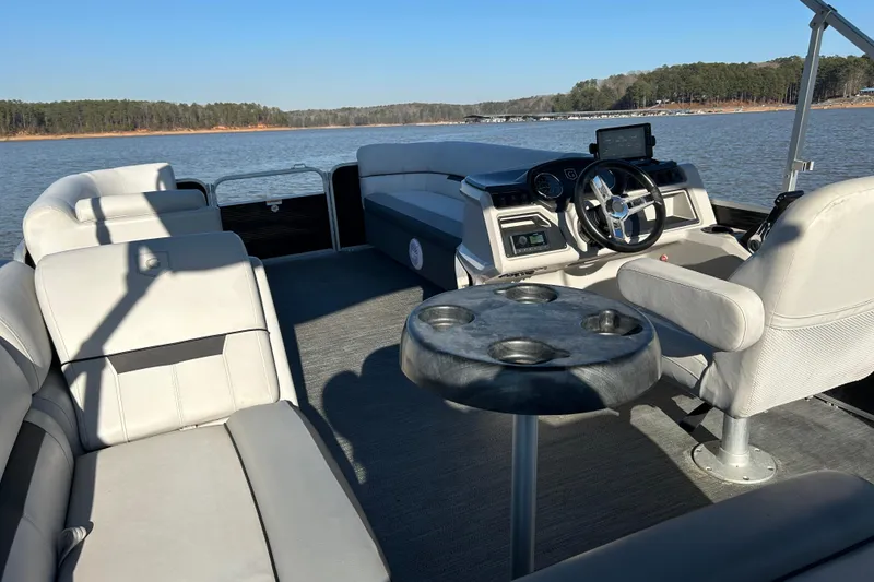 Slide: The Image of 2022 Godfrey Sweetwater 2286 C pontoon boat interior with seating and steering wheel on a lake. - 18