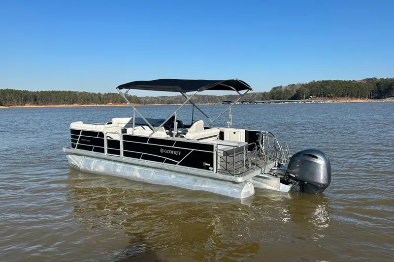 Slide: The Image of 2022 Godfrey Sweetwater 2286 C pontoon boat on a calm lake under clear blue skies. - 3