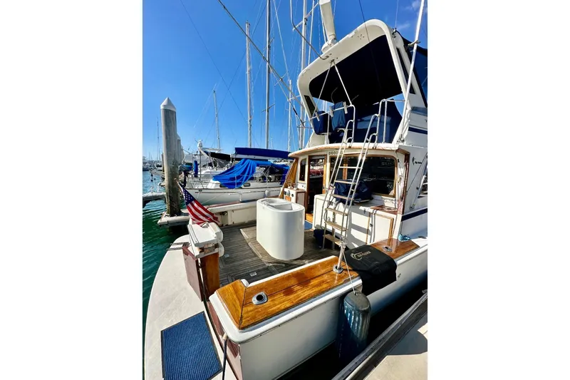 Slide: The Image of 1987 Egg Harbor 43 Sport Fisherman docked at marina, featuring wooden deck and American flag. - 2