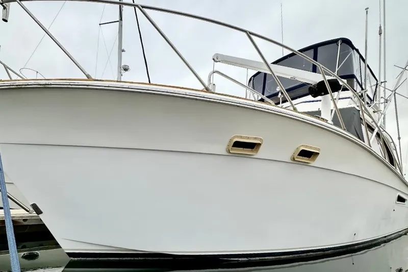 Slide: The Image of 1987 Egg Harbor 43 Sport Fisherman boat docked, showcasing sleek white hull and railing. - 24