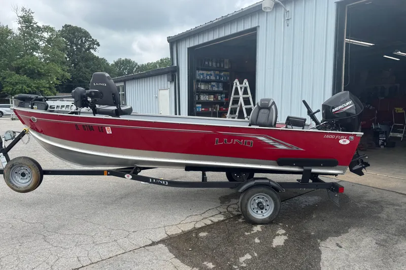 The Image of 2023 Lund 1600 Fury Tiller boat on trailer, parked outside a garage. - 0