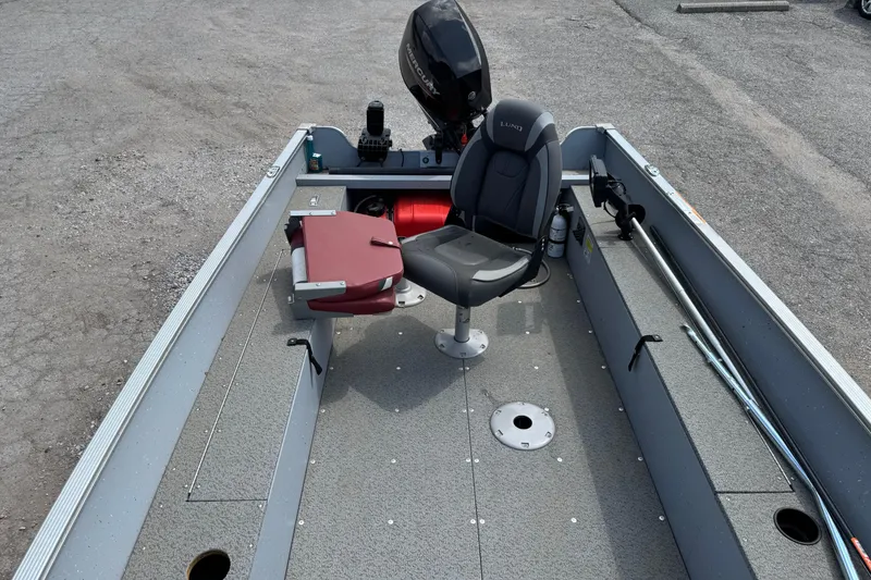 Slide: The Image of 2023 Lund 1600 Fury Tiller boat interior with seating and motor, parked on gravel. - 6