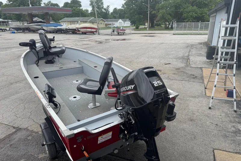 Slide: The Image of 2023 Lund 1600 Fury Tiller boat with Mercury 25 engine in a parking lot. - 9