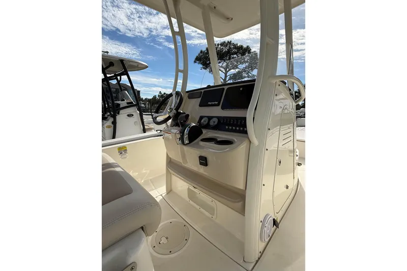 Slide: The Image of 2020 Boston Whaler 240 Dauntless boat console with steering wheel and controls under a clear sky. - 11