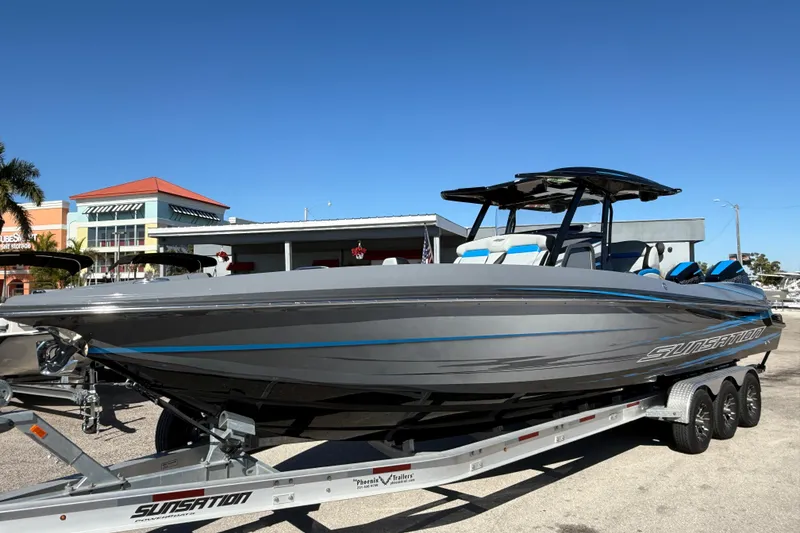 The Image of 2026 Sunsation 32 CCX boat on trailer, sleek gray design, sunny day backdrop. - 1