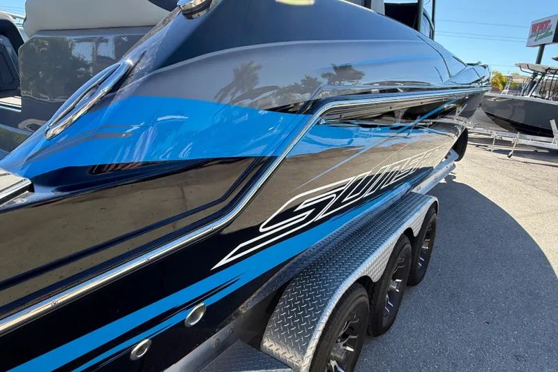Slide: The Image of 2026 Sunsation 32 CCX boat with sleek blue and black design on a trailer. - 12
