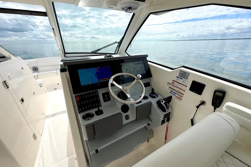 Slide: The Image of 2024 Pursuit DC 365 Dual Console boat interior with modern dashboard and ocean view. - 16