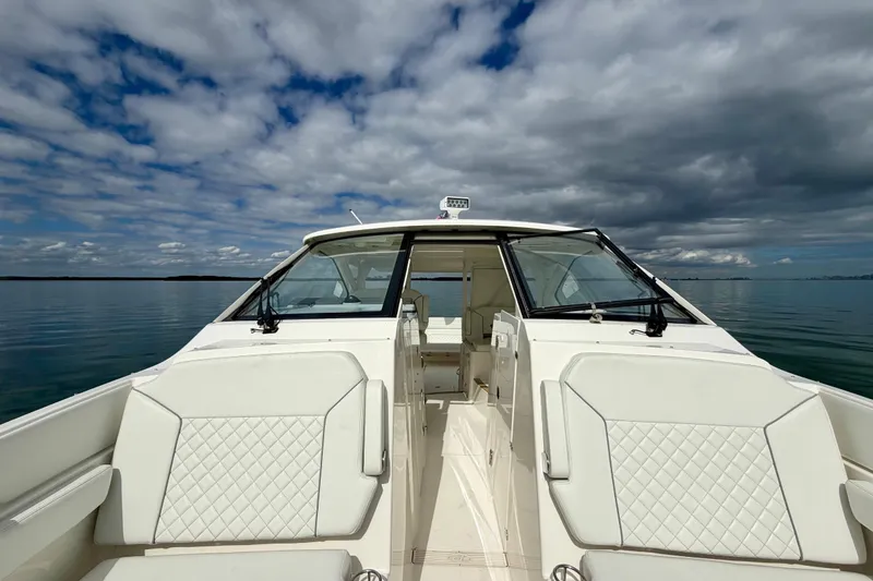 Slide: The Image of 2024 Pursuit DC 365 Dual Console boat on calm water under cloudy sky. - 24