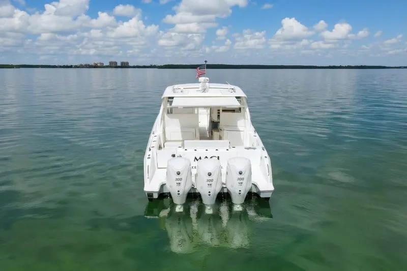 Slide: The Image of 2024 Pursuit DC 365 Dual Console boat on calm water, rear view with triple engines. - 5