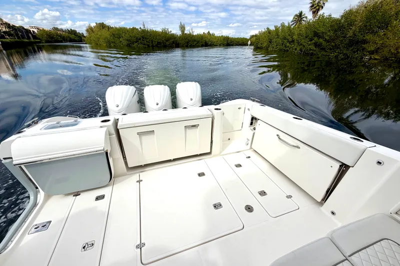 Slide: The Image of 2024 Pursuit DC 365 Dual Console boat on serene waterway, showcasing spacious deck. - 7