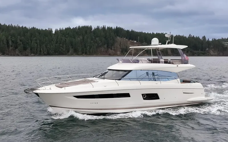 The Image of 2017 Prestige 560 yacht cruising on a scenic lake with forested shoreline. - 0