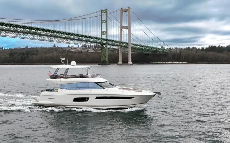 Slide: The Image of 2017 Prestige 560 yacht cruising under a large suspension bridge on a cloudy day. - 48