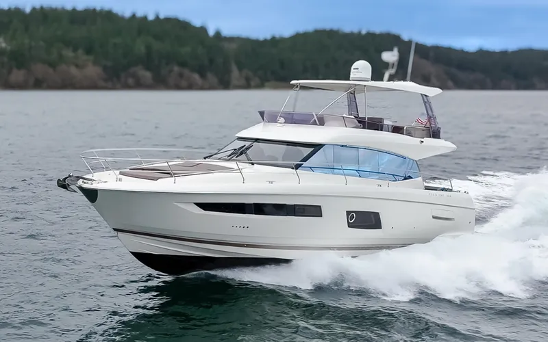 Slide: The Image of 2017 Prestige 560 yacht cruising on open water, surrounded by lush greenery. - 5