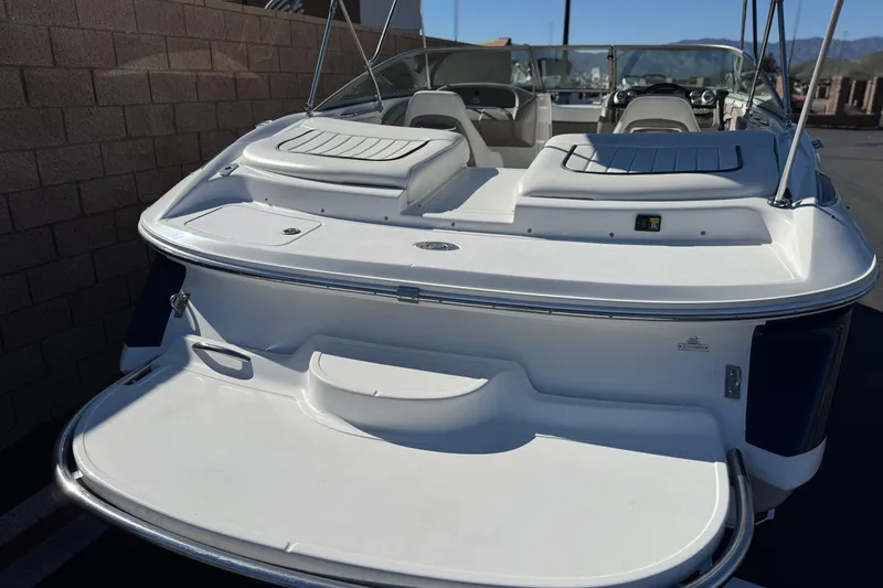 Slide: The Image of 2005 Cobalt 200 boat with open deck and seating, parked near a brick wall. - 6