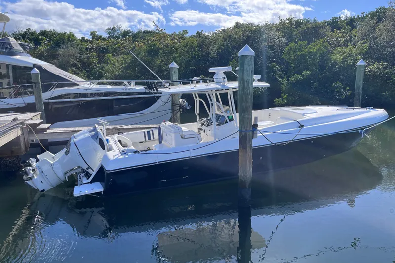 Slide: The Image of 2008 Intrepid 370 Cuddy boat docked in a serene marina setting. - 2