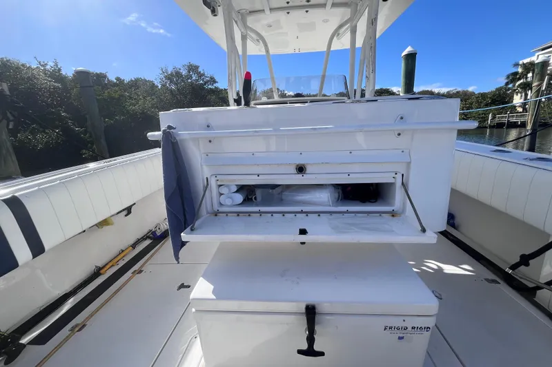 Slide: The Image of 2008 Intrepid 370 Cuddy boat interior with seating and storage, docked by the water. - 24