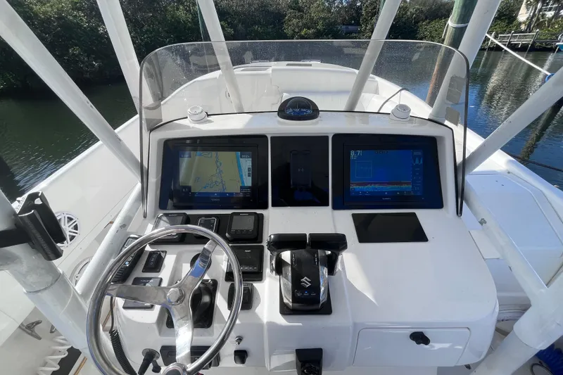 Slide: The Image of 2008 Intrepid 370 Cuddy boat interior with helm and seating, docked by water. - 26