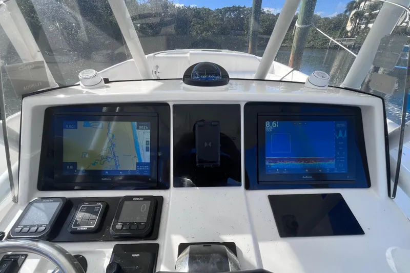 Slide: The Image of 2008 Intrepid 370 Cuddy helm with navigation screens and steering wheel, docked by water. - 27