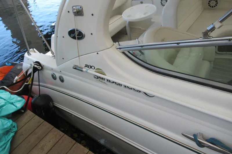 Slide: The Image of 2001 Searay 280 Sundancer boat docked, showing sleek white exterior and interior seating. - 13